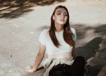 a woman sitting on the ground in a white top