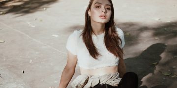 a woman sitting on the ground in a white top