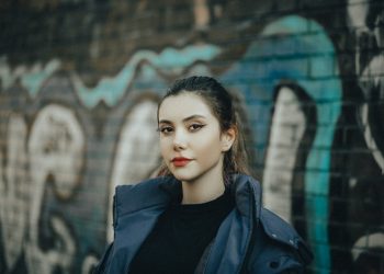 a woman standing in front of a graffiti covered wall