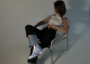 Woman sits in a chair, striking a pose.