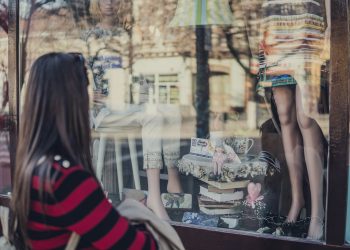 woman standing near store while looking at the mannequin