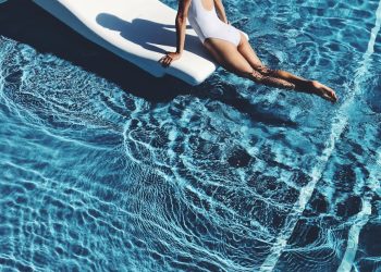 woman lying on white lounge chair in the middle of pool