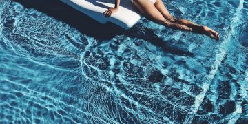 woman lying on white lounge chair in the middle of pool