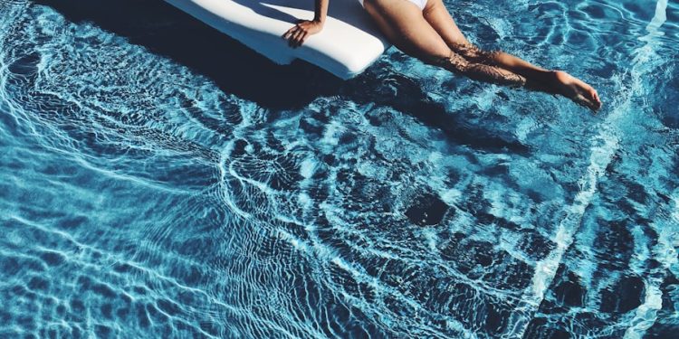 woman lying on white lounge chair in the middle of pool