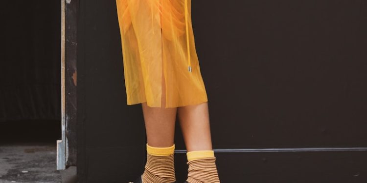 a woman in a white sweater and yellow skirt