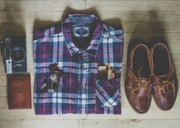 flat lay photography of button-up shirt, camera, keys, cigarettes, and pair of brown leather boat shoes